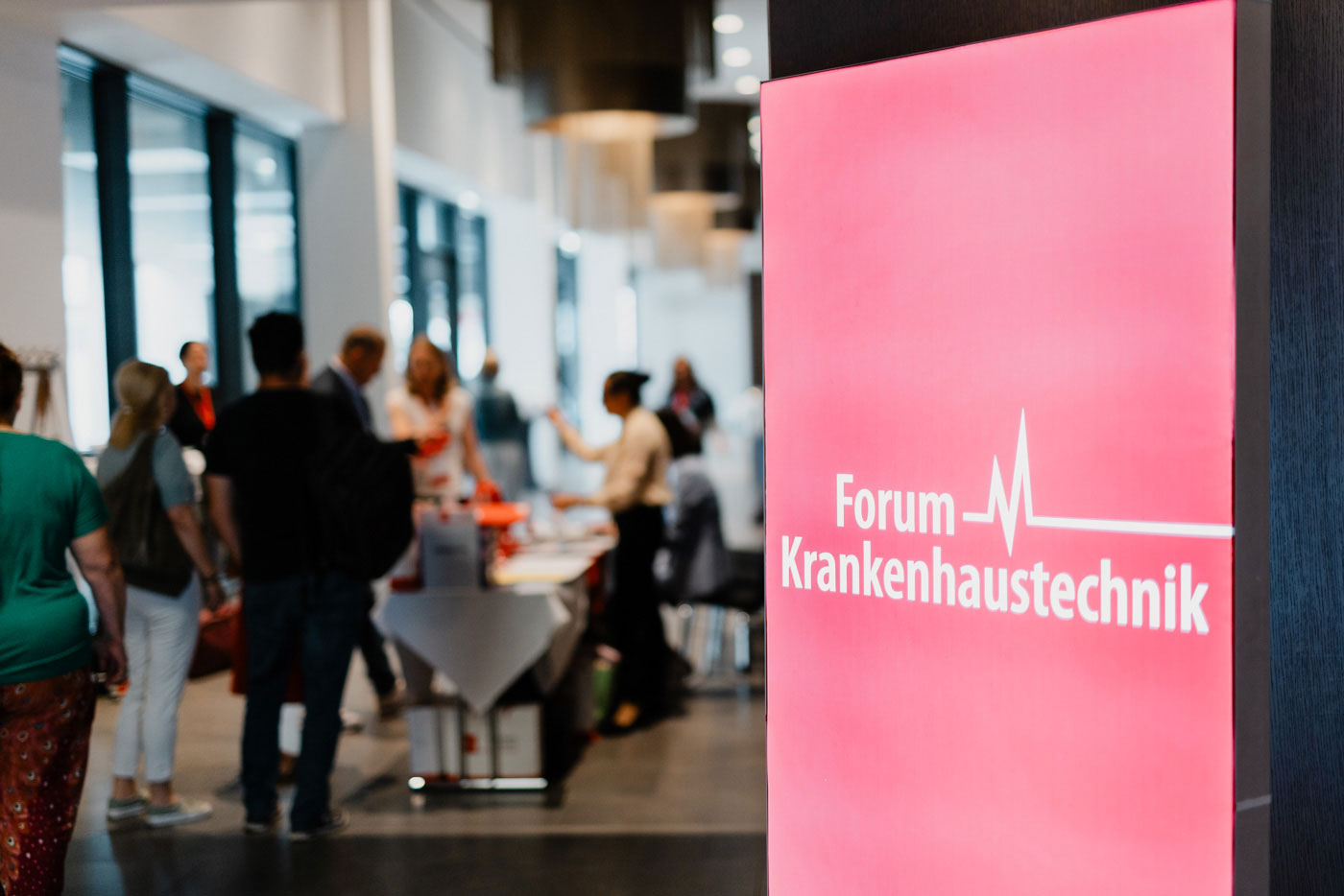 Ein rotes RollUp des Forum Krankenhaustechnik von imh mit dem Konferenz-Check-In im Hitnergrund