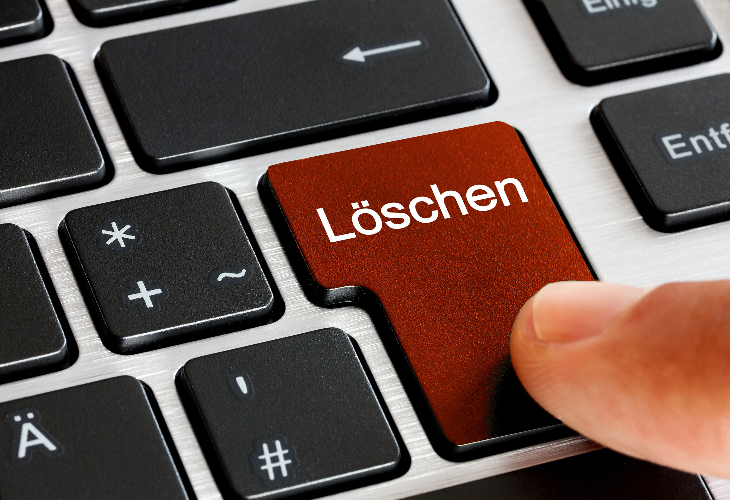 Finger drückt auf rote Taste "Löschen" auf Tastatur