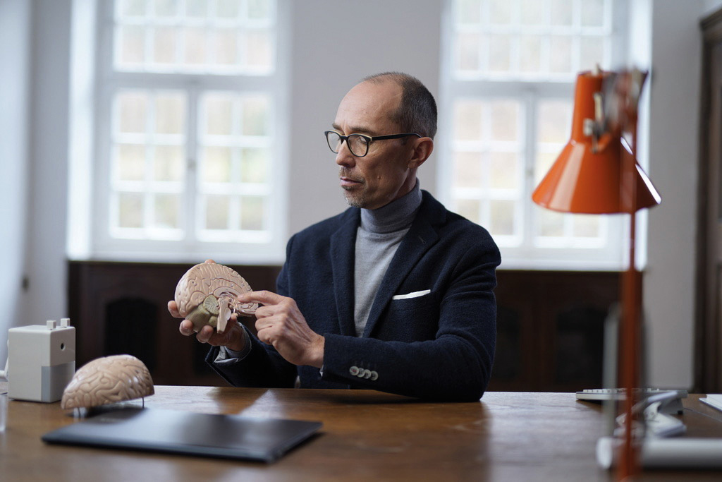 Bernd Hufnagl sitzt an einem Tisch, er hält eine Gehirnhälfte in der Hand, die andere liegt auf der Tischplatte