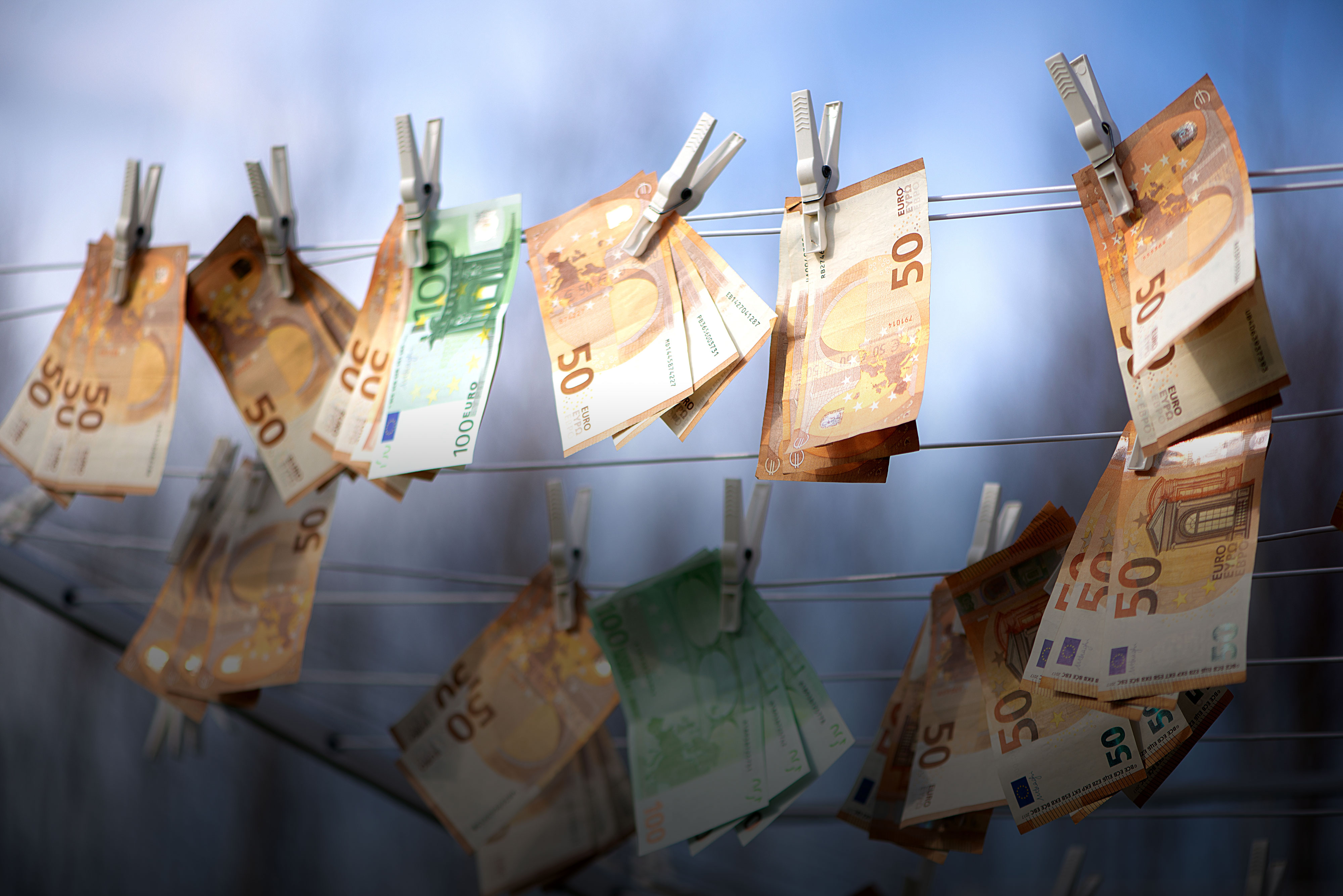 50-Euro und 100-Euro Geldscheine hängen auf einer Wäscheleine zum Trocknen