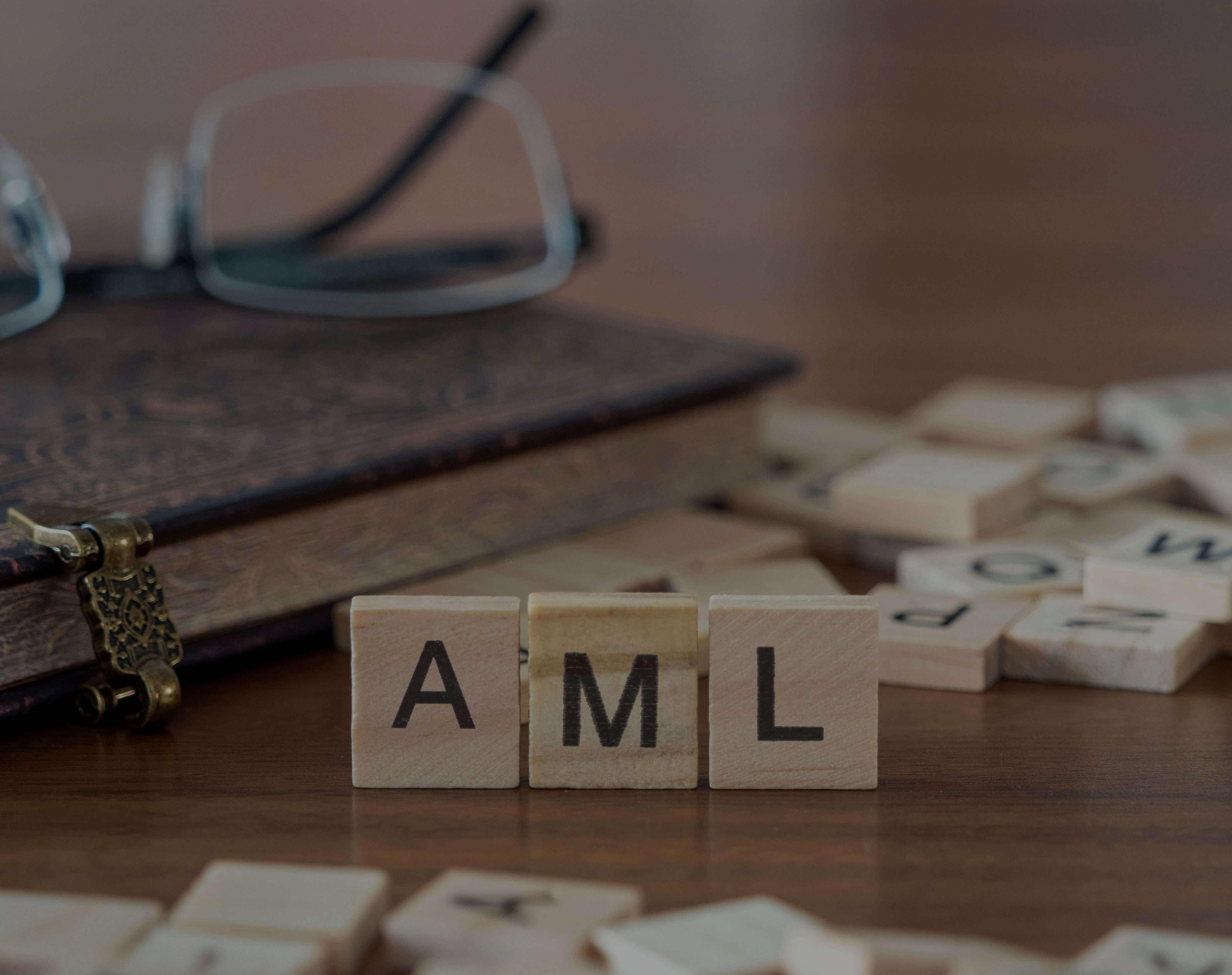 Auf einem Tisch stehen drei Holzwürfel, auf denen jeweils die Buchstaben A, M und L zu sehen sind