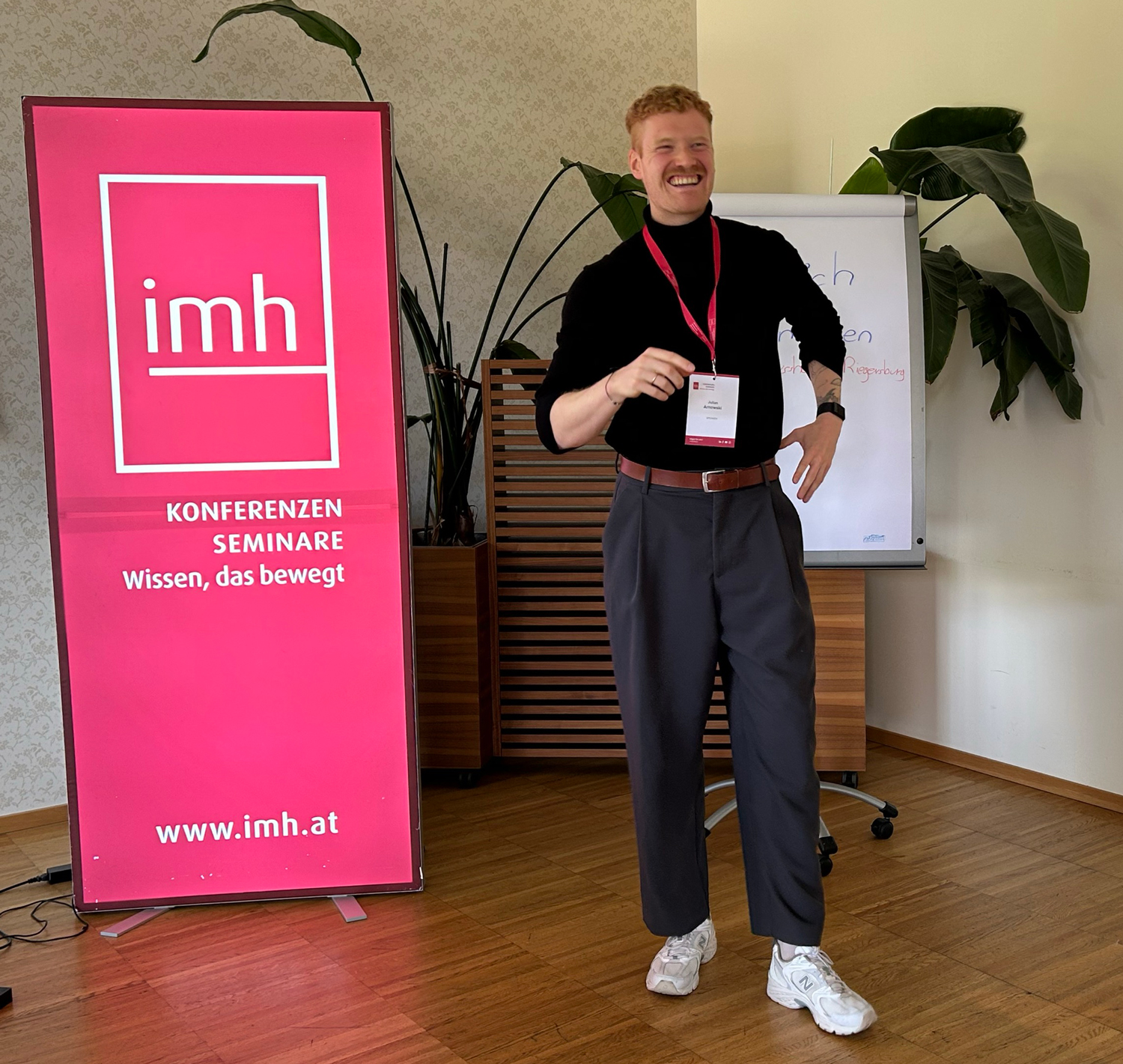Julian Arnowski steht lächelnd vor imh Roll-up.