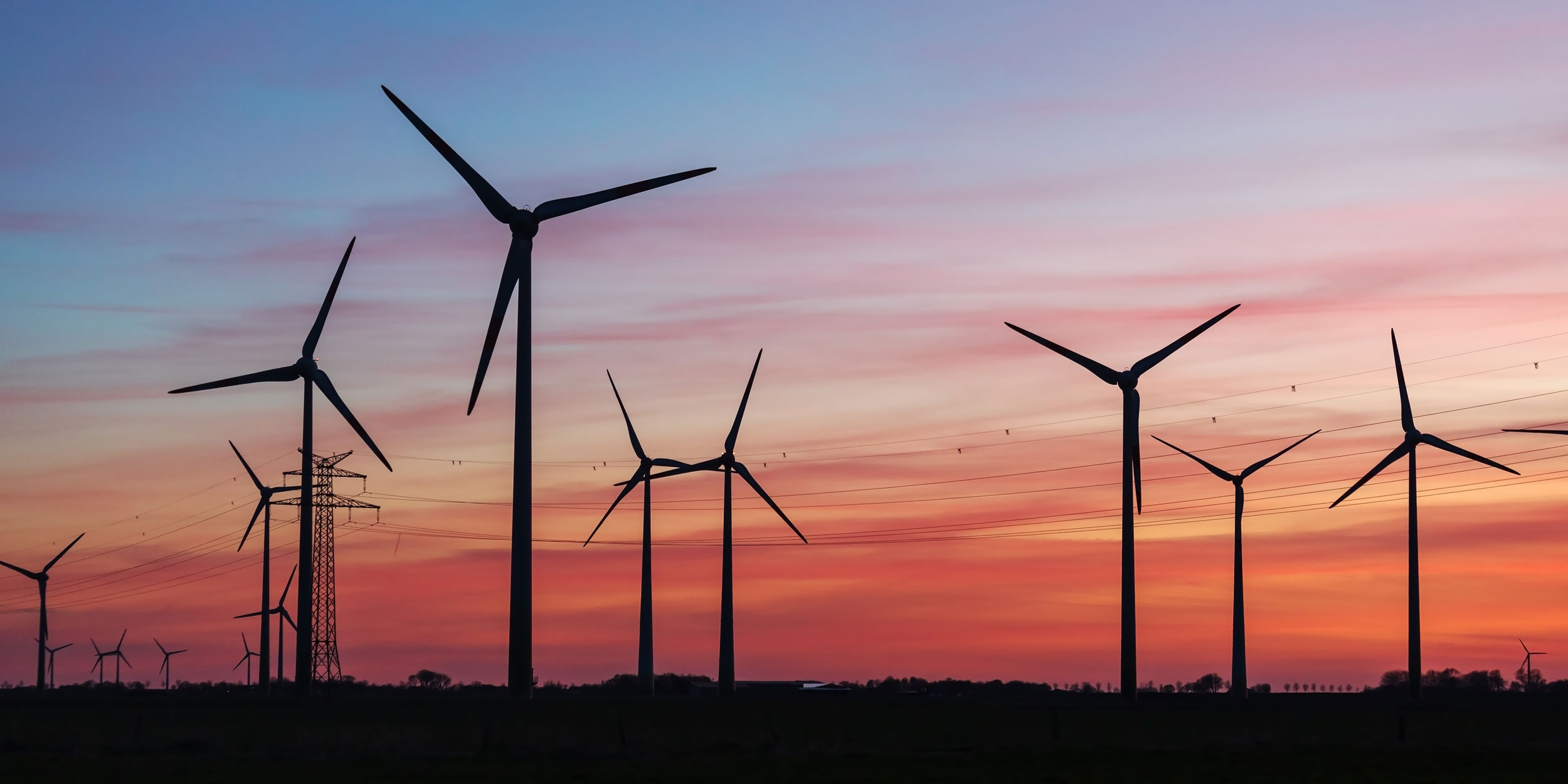 Windräder drehen sich in der Abendsonne.