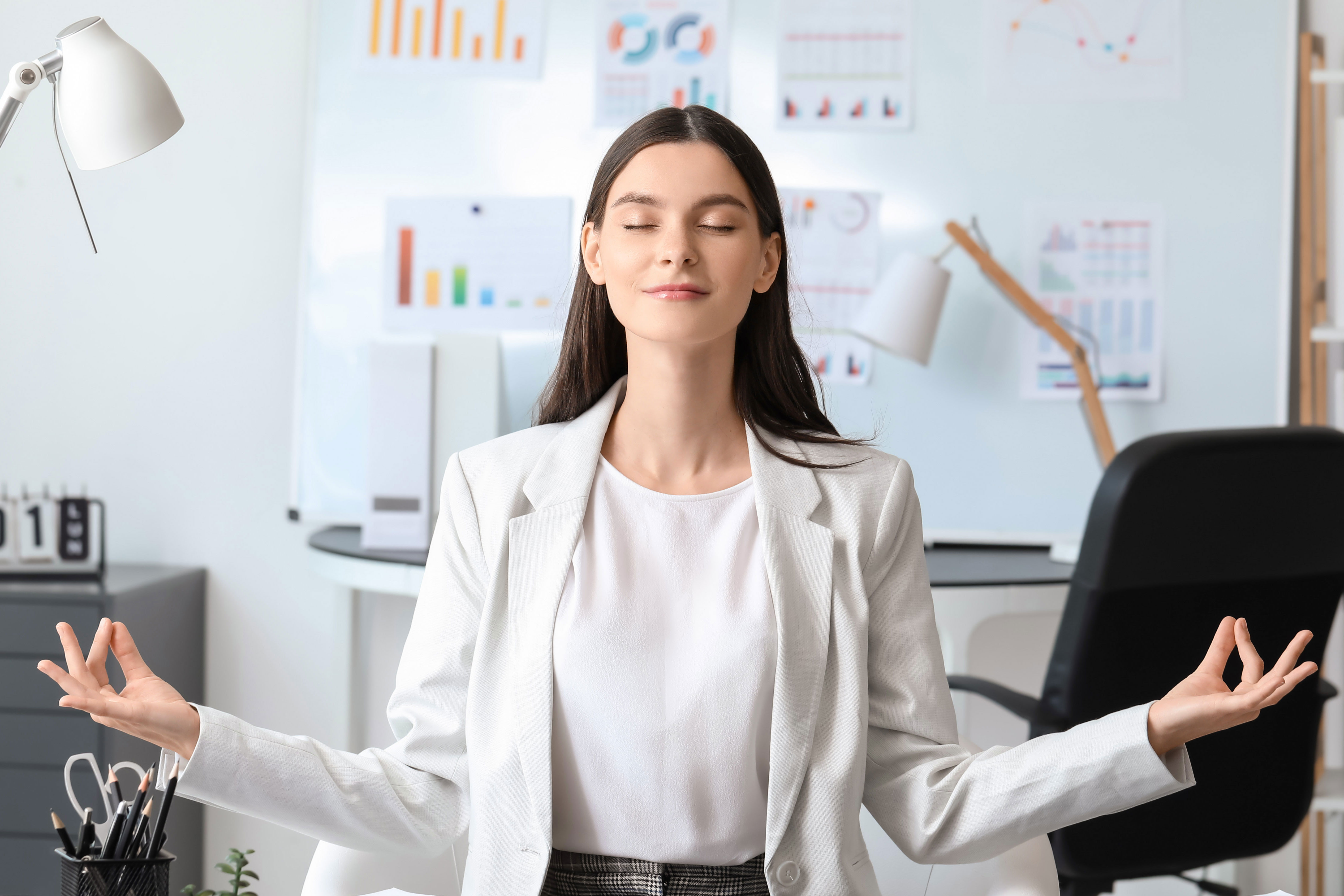 Eine Dame sitzt im Büro und ist im Einklang mit sich selbst, da sie meditiert 