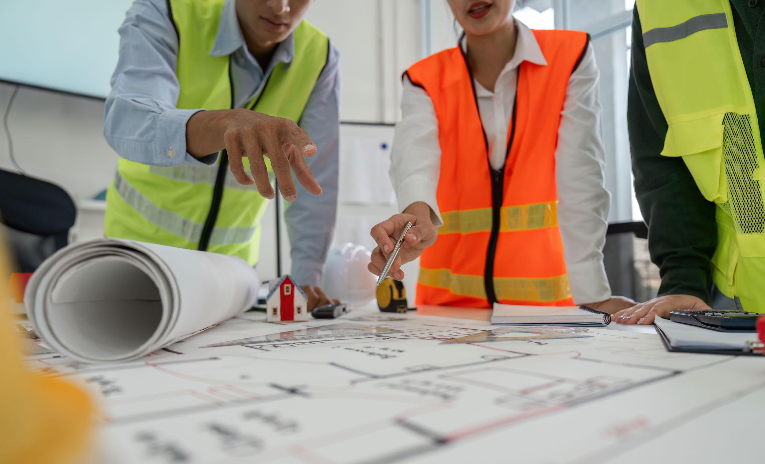 Bauprojektmanager in Warnwesten schauen sich einen Bauplan an 