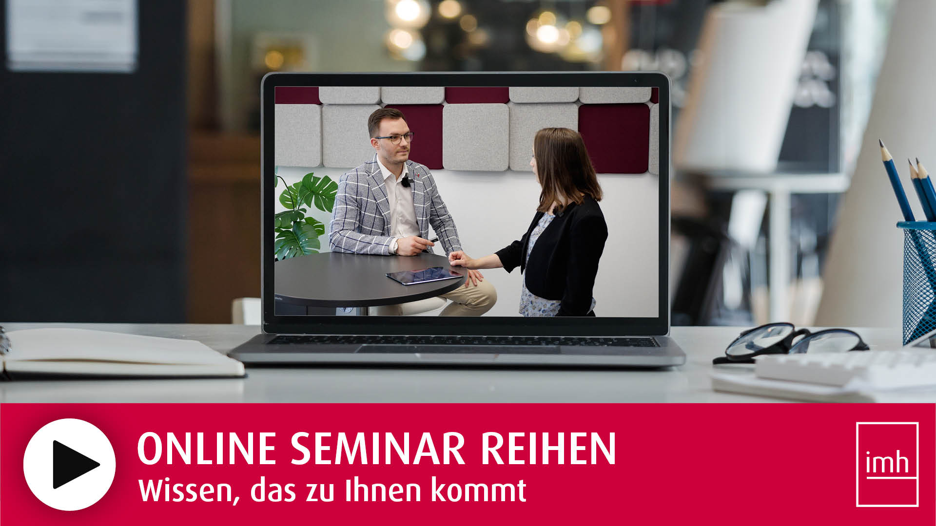 Auf einem Schreibtisch steht ein Laptop auf dem das imh Online Seminar Reihen Erklärvideo abgespeilt wird.