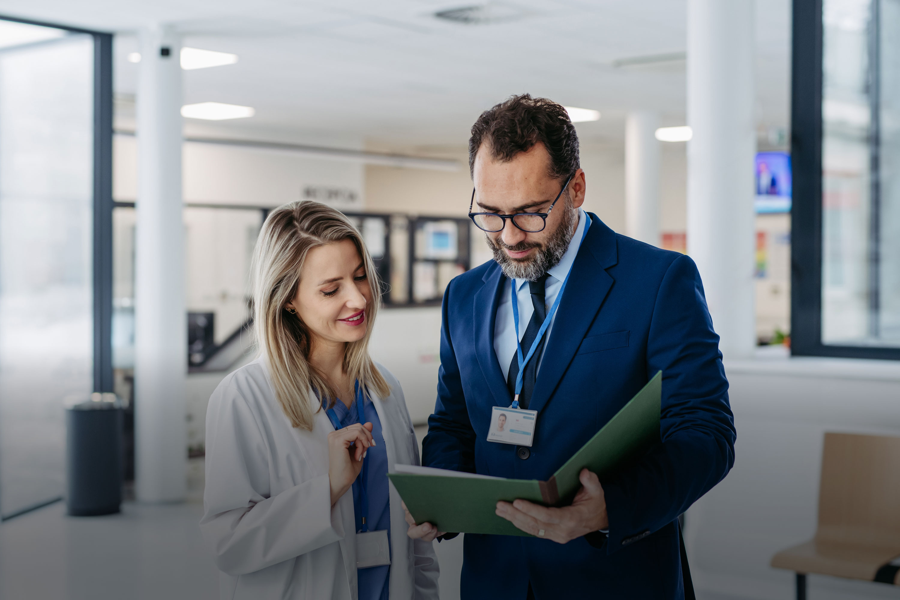 Zwei Personen in einem Krankenhaus schauen in eine Mappe und besprechen sich