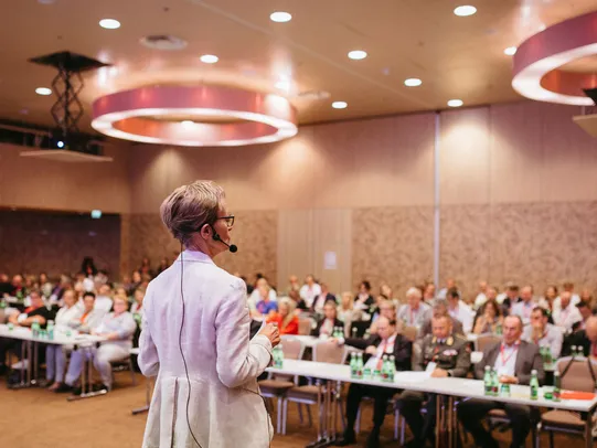 Referentin Vor Publikum in einem vollen Raum mit warmen Licht