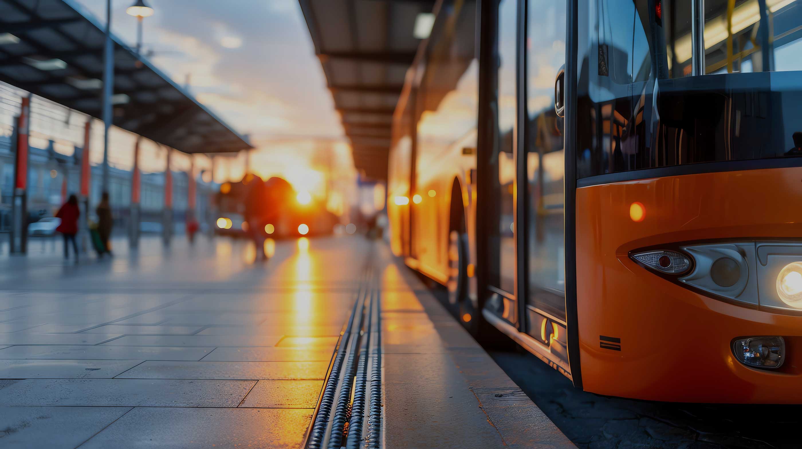 Ein orangener Bus fährt in der Abendsonne.