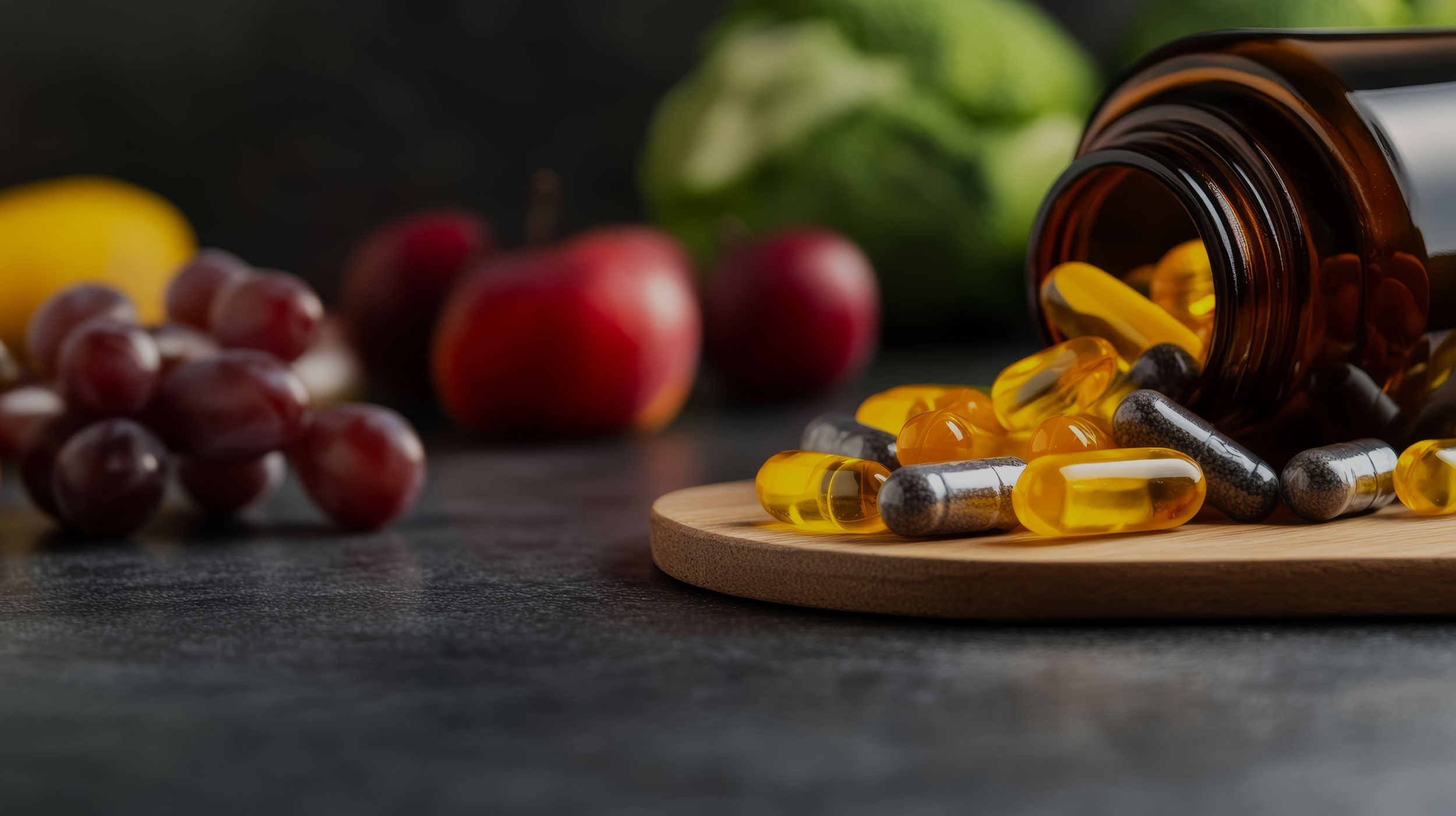 Auf einem Holzbrett liegt ein umgekipptes Tablettenglas. Im Hintergrund sieht man Obst und Gemüse.